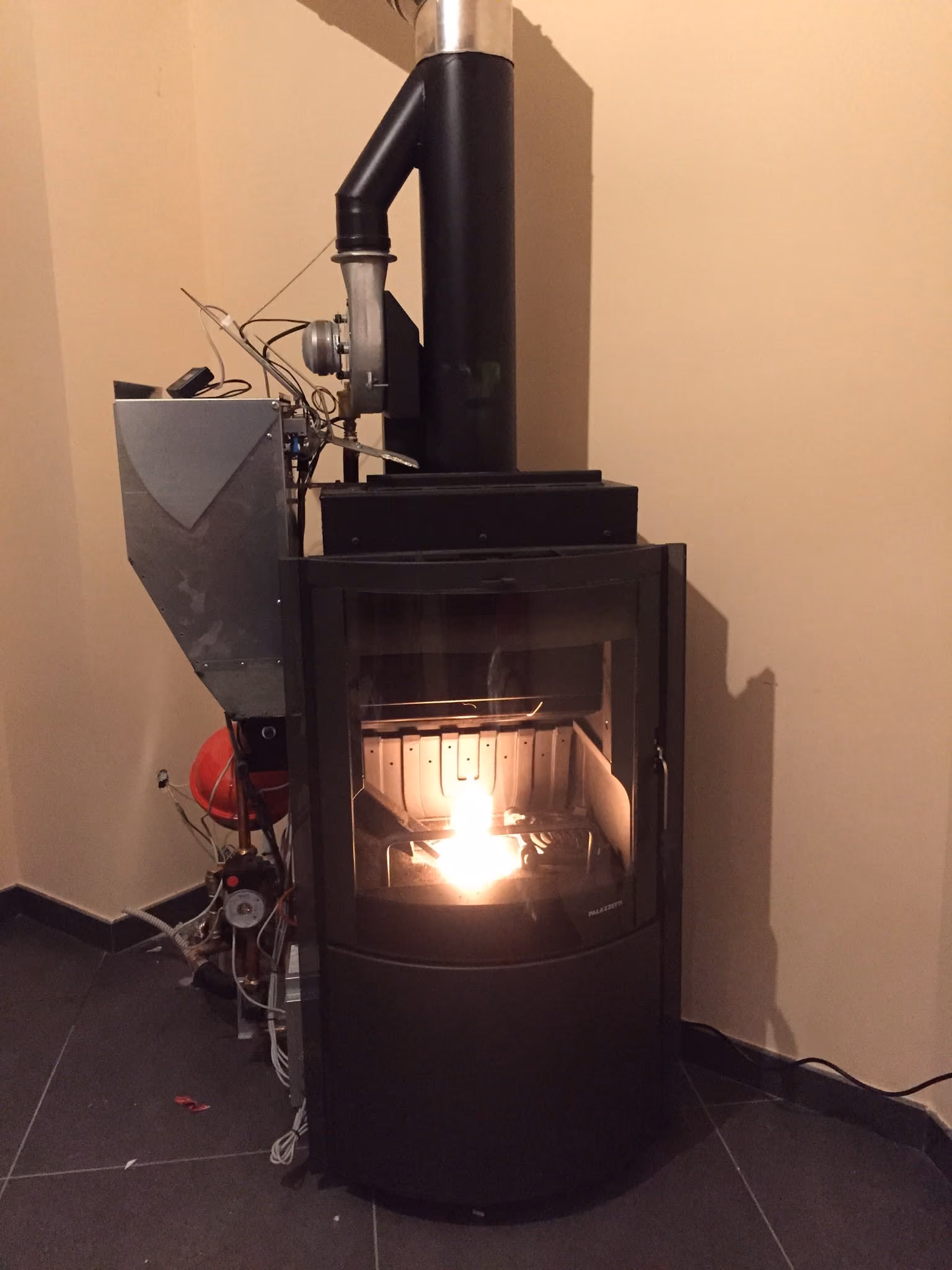 Stufa installata a parete in un ambiente di casa, con il fuoco acceso.